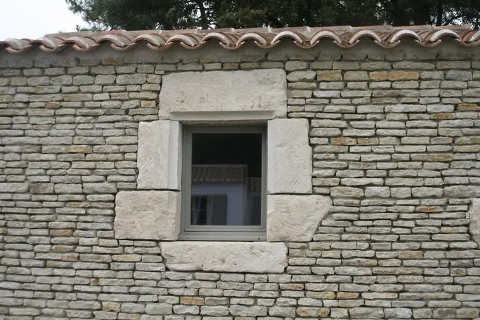 Fenêtre à encadrement de pierre dans un mur en moellons