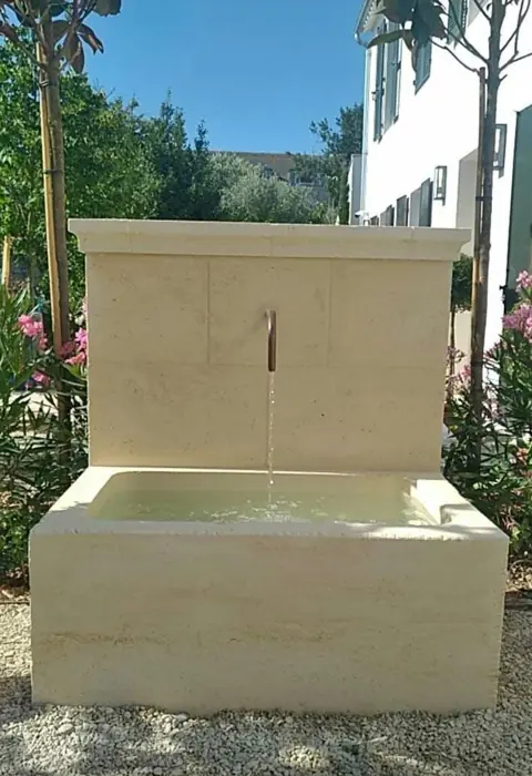 Fontaine murale en pierre de taille dans un jardin