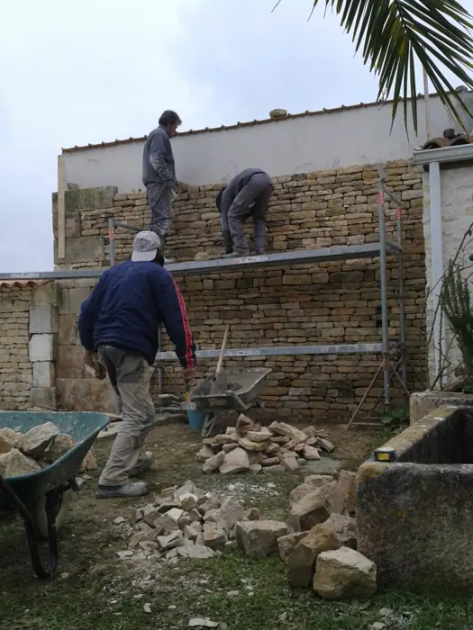 Montage d'un mur en pierre sèche sur échafaudage